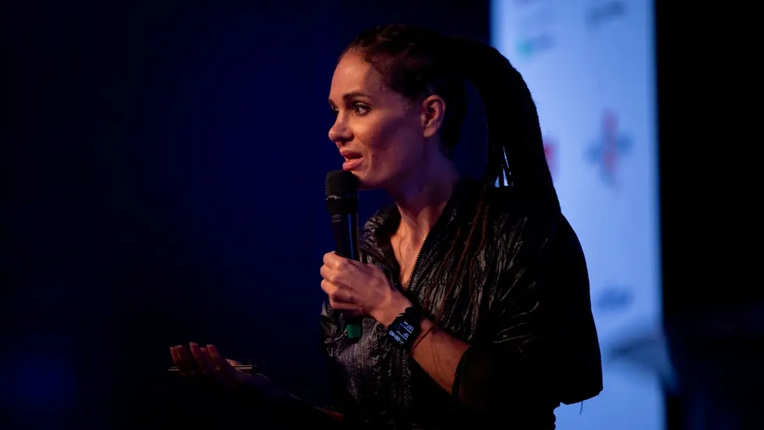 Close-up of Monica Magalhaes speaking into the microphone during a talk
