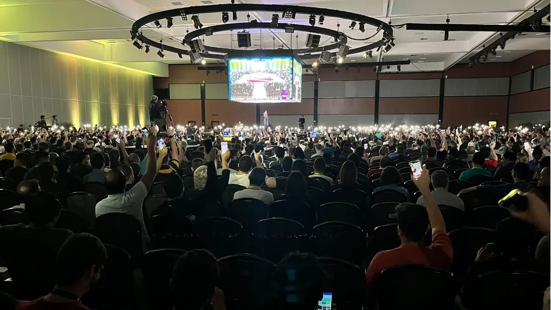 Auditorium audience with phone flashlights lit during the talk